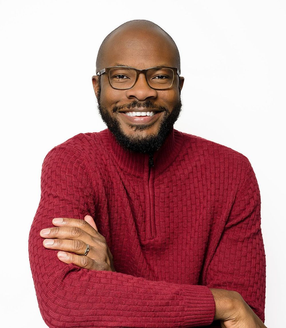 Tiem Okori, photographer, smiling in a red sweater