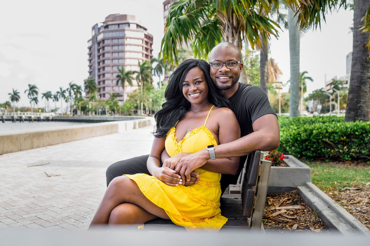 Couple seated together on a bench along a waterfront promenade
