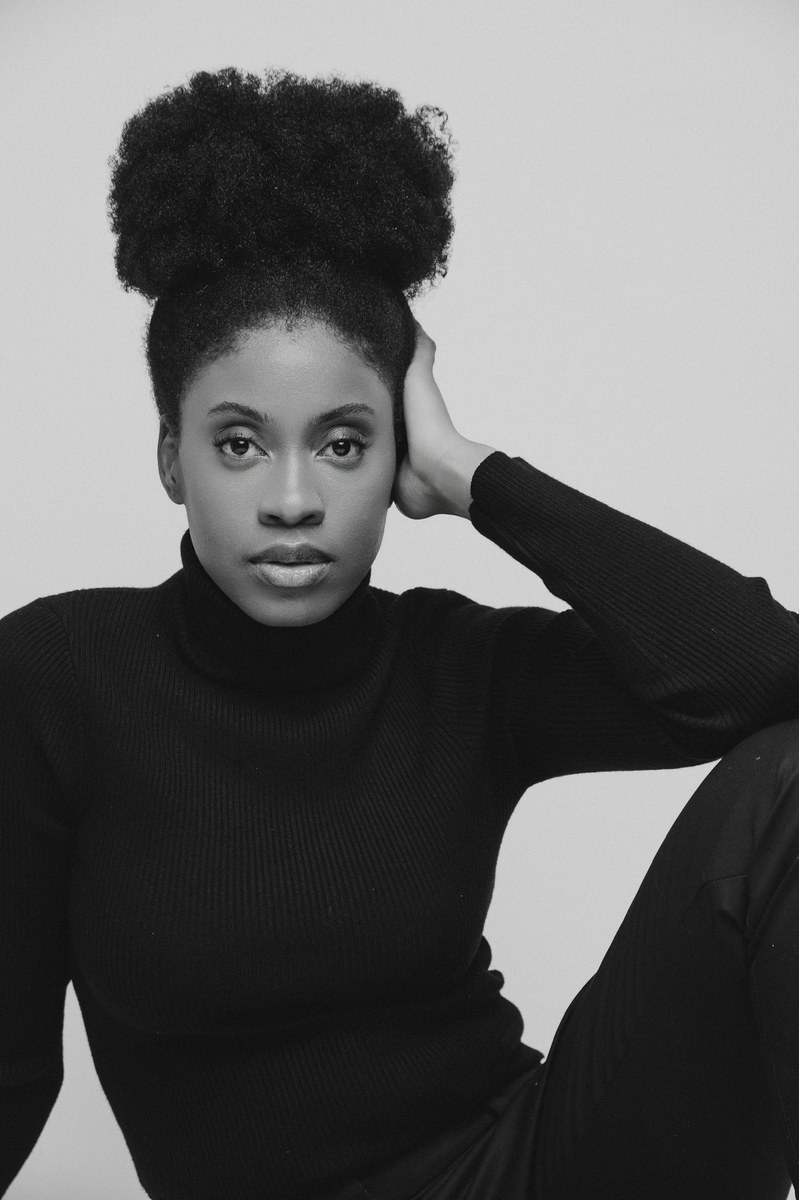 Black and white portrait of a woman in a black turtleneck with her hair in a high bun